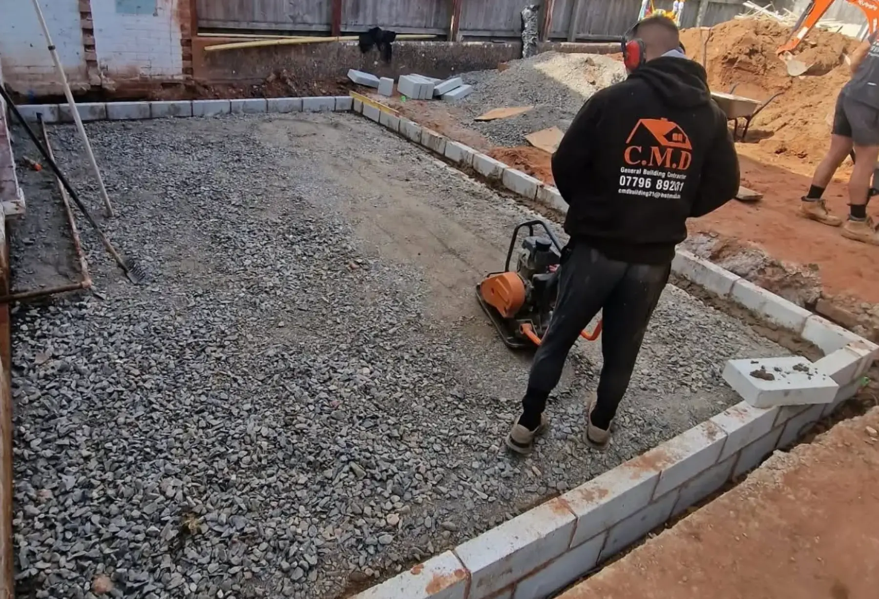 CMD operative compacting a new driveway sub-base with plate compactor
